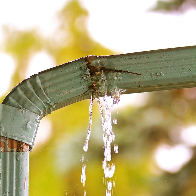 A broken downspout leaks water.